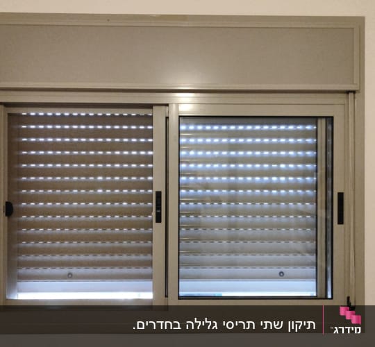תריסים סגורים בחלון עם מסגרת מתכת אפורה